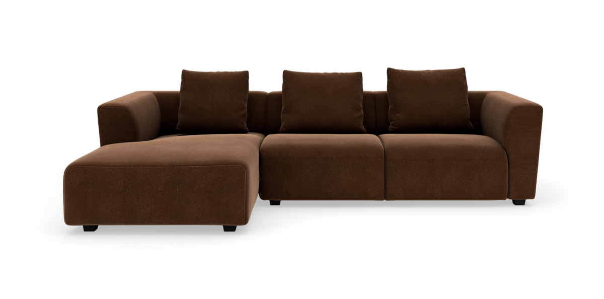 Brun modulsofa med venstrevendt chaiselong, tre sædemoduler og tre puder, frilagt på hvid baggrund.