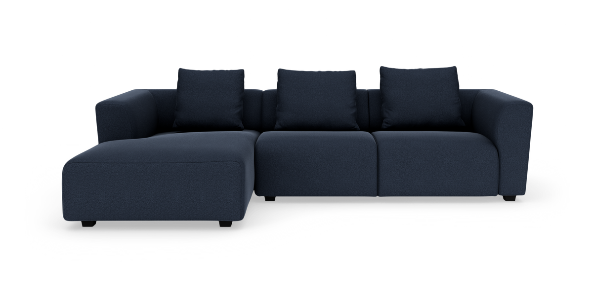 Mørkeblå modulsofa med venstrevendt chaiselong og tre ryghynder, frilagt på hvid baggrund.