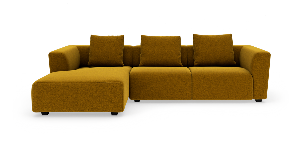 Modulsofa i sennepsgul stof med venstrevendt chaiselong og tre ryghynder, frilagt på hvid baggrund.