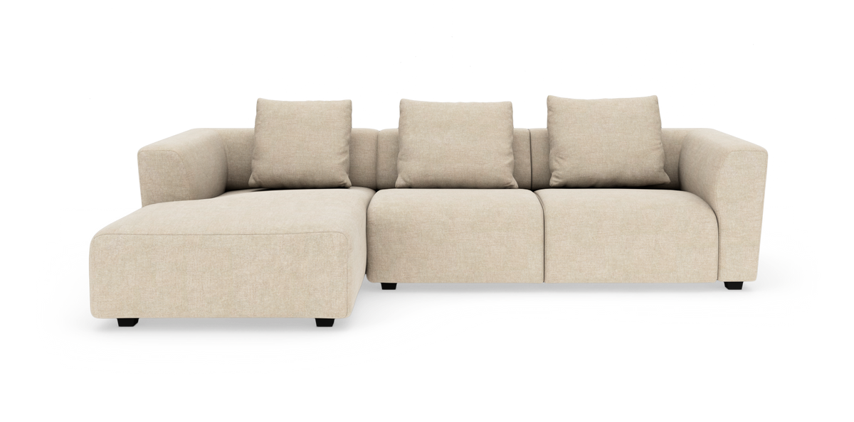 Beige modulsofa med chaiselong til venstre og tre rygpuder, frilagt på hvid baggrund.