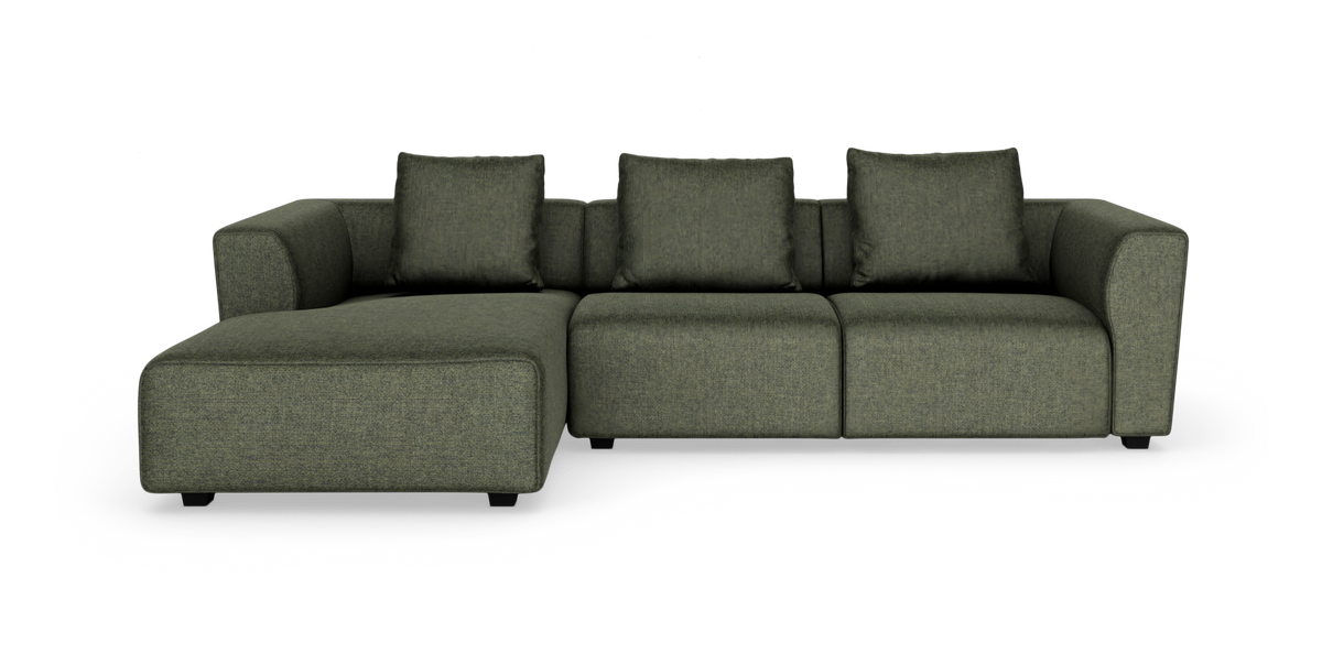 Modulsofa i mosgrønt stof med venstrevendt chaiselong og fire puder, frilagt på hvid baggrund.