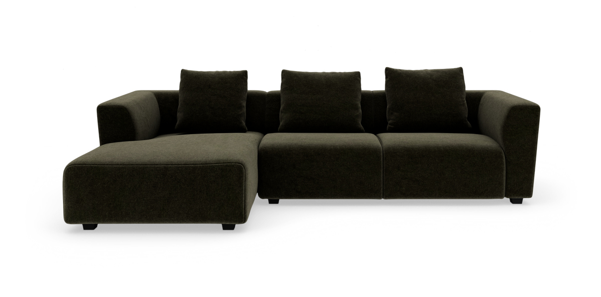 Modulsofa i mørk olivgrøn tekstil med venstrevendt chaiselong og tre løse ryghynder, fritstående på hvid baggrund.