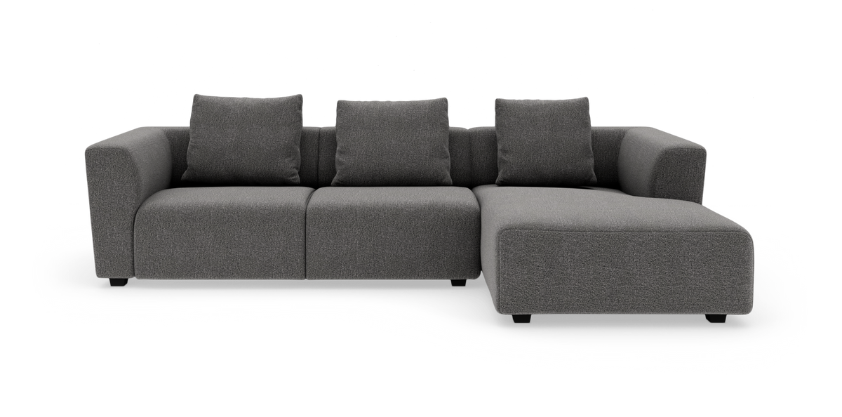 Mørkegrå modulsofa med chaiselong til højre og tre rygpuder, frilagt på hvid baggrund.
