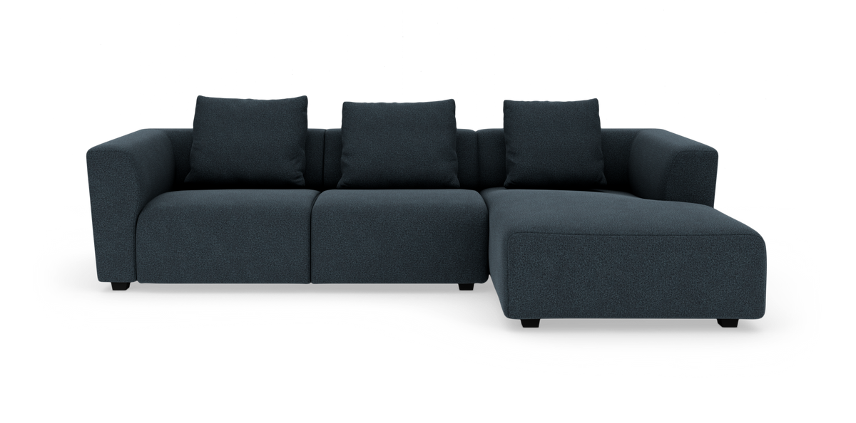 Mørkeblå modulsofa med chaiselong til højre og tre rygpuder, set forfra.