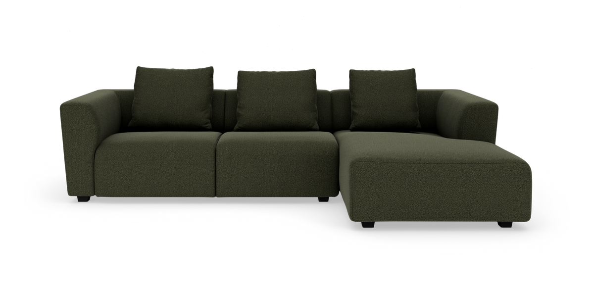 Mørkegrøn L‑sofa med højrevendt chaiselong og fire ryghynder, fritlagt på hvid baggrund.