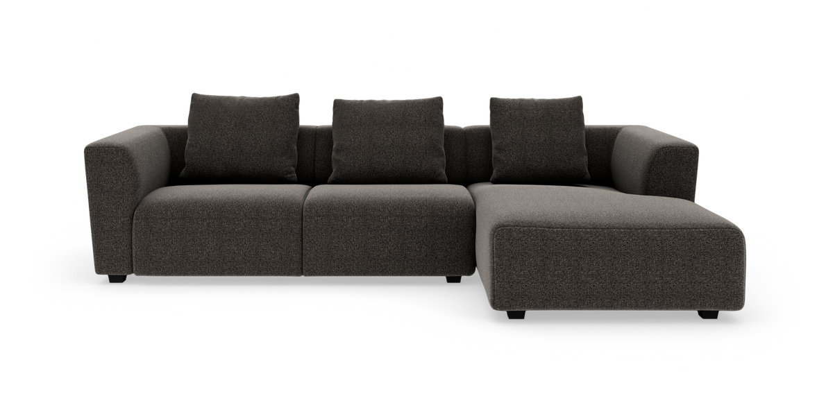 Mørkegrå modulsofa med chaiselong til højre, fotograferet forfra mod hvid baggrund.