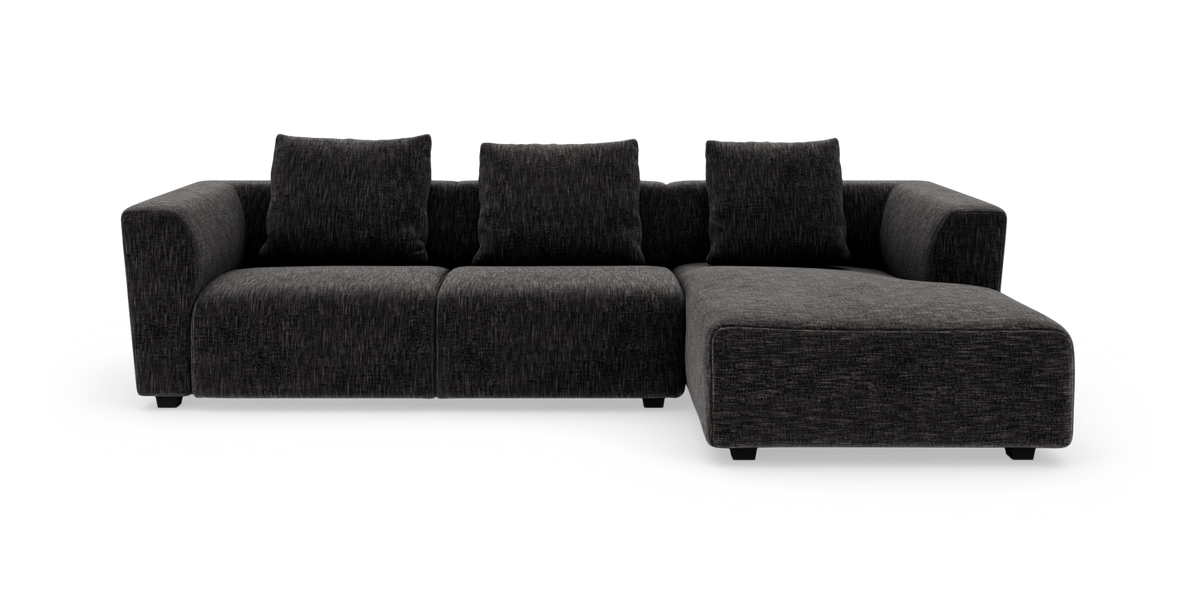 Mørkegrå modulsofa med chaiselong til højre og tre rygpuder, frilagt på hvid baggrund.