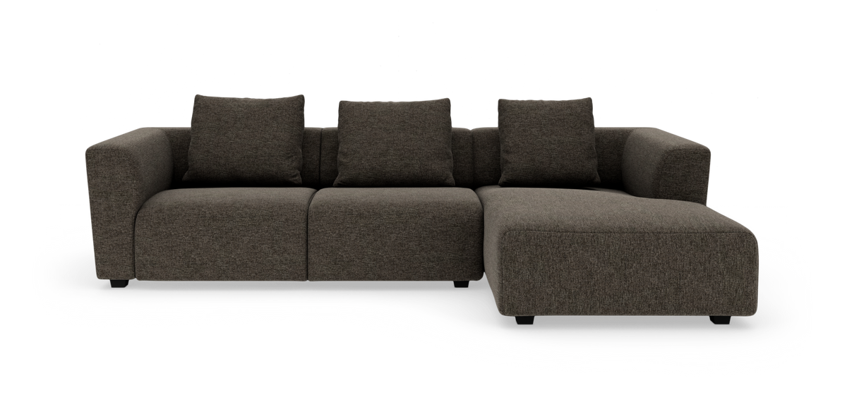 Mørkegrå modulsofa med chaiselong til højre og tre ryghynder, centreret mod hvid baggrund.