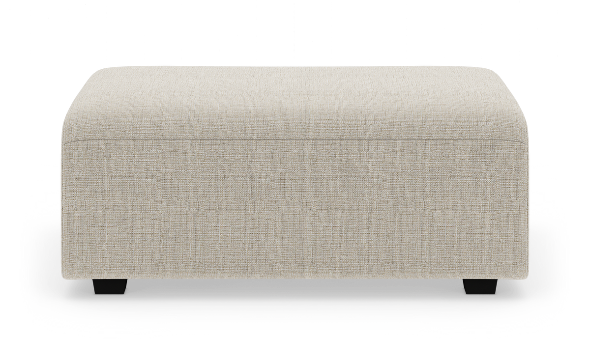 Beige stofbetrukket puf/ottoman på hvid baggrund, frontvisning.