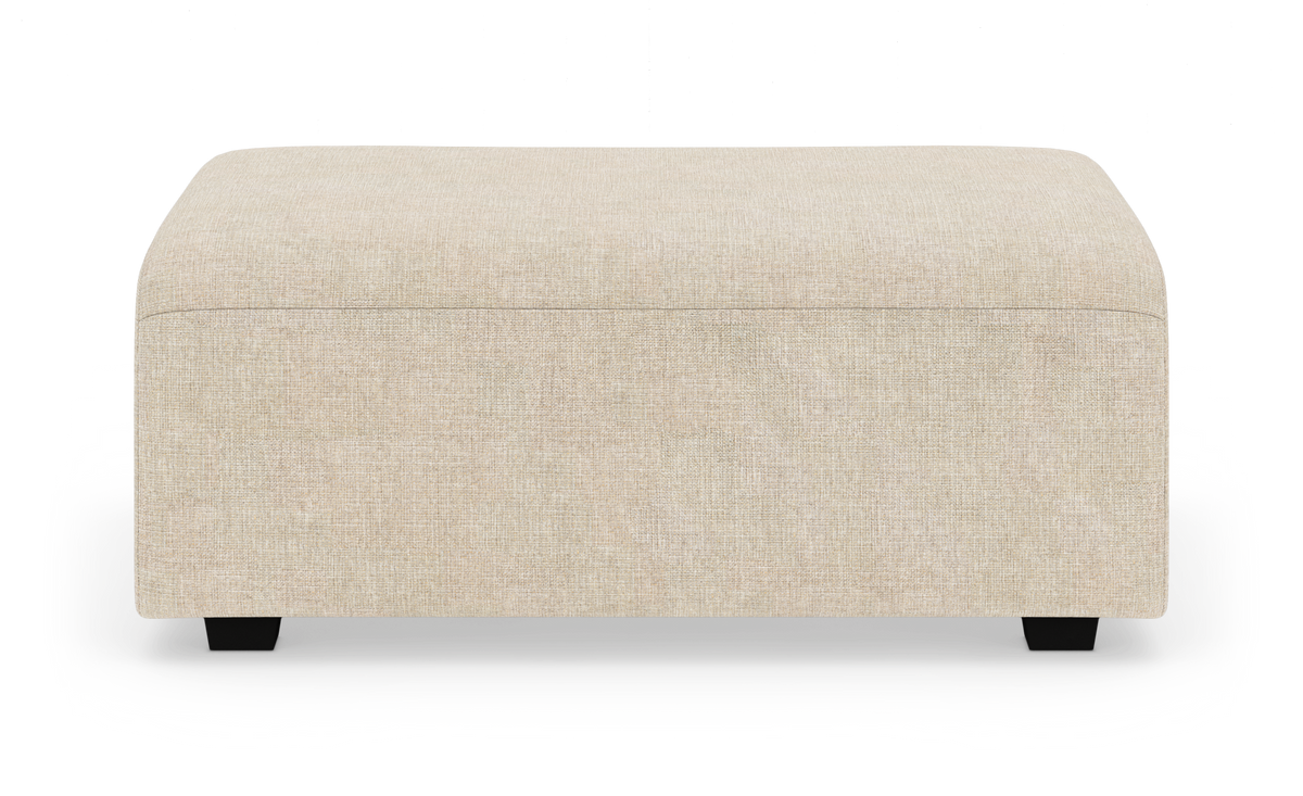 Beige rektangulær puf/ottoman med lave sorte ben frilagt på hvid baggrund.