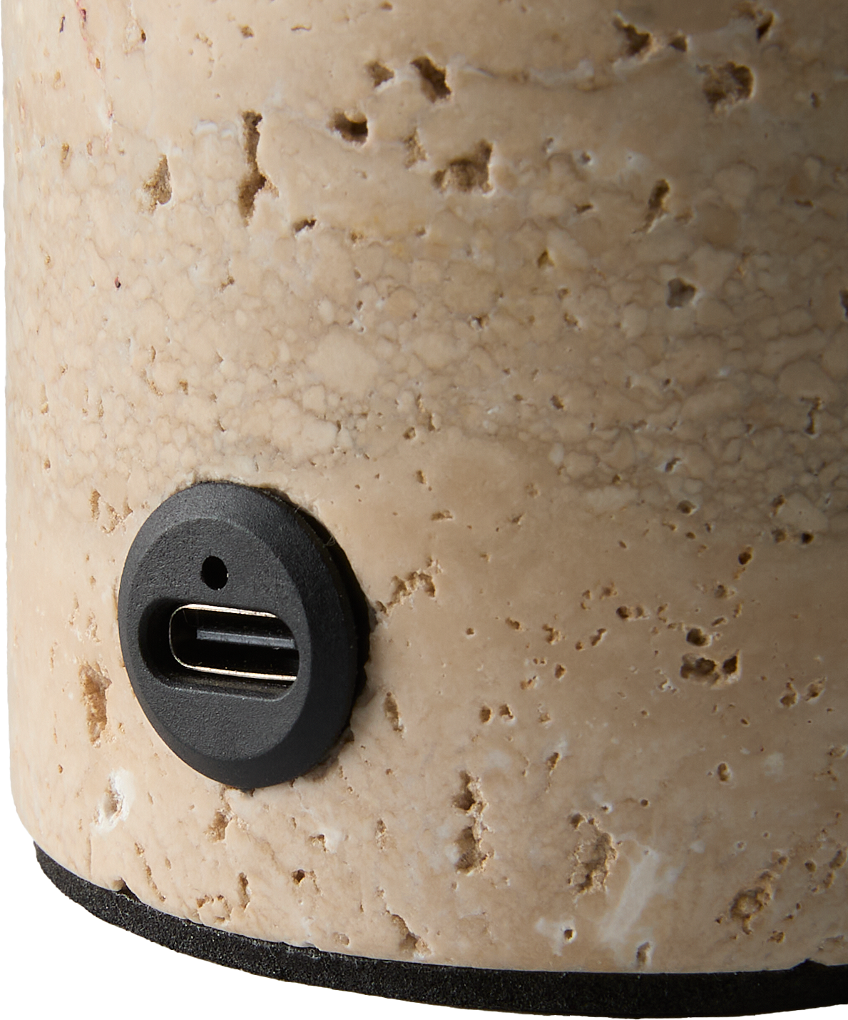 Nærbillede af en USB‑C-port i sort indfatning på et beige stenlignende cylindrisk produkt.
