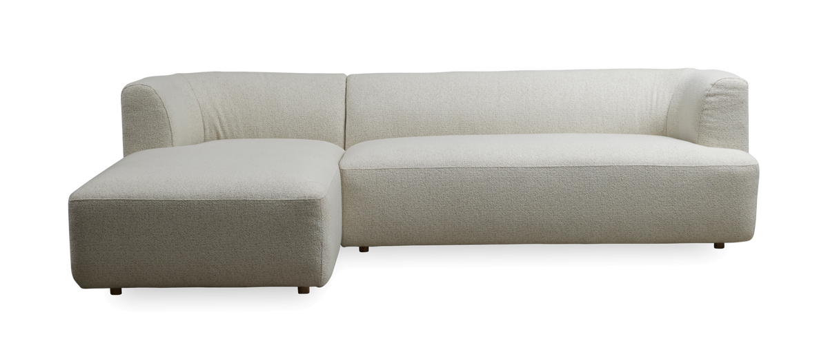 L‑formet lys beige hjørnesofa med venstrevendt chaiselong, bløde afrundede former i boucléstof, frilagt på mørk baggrund.