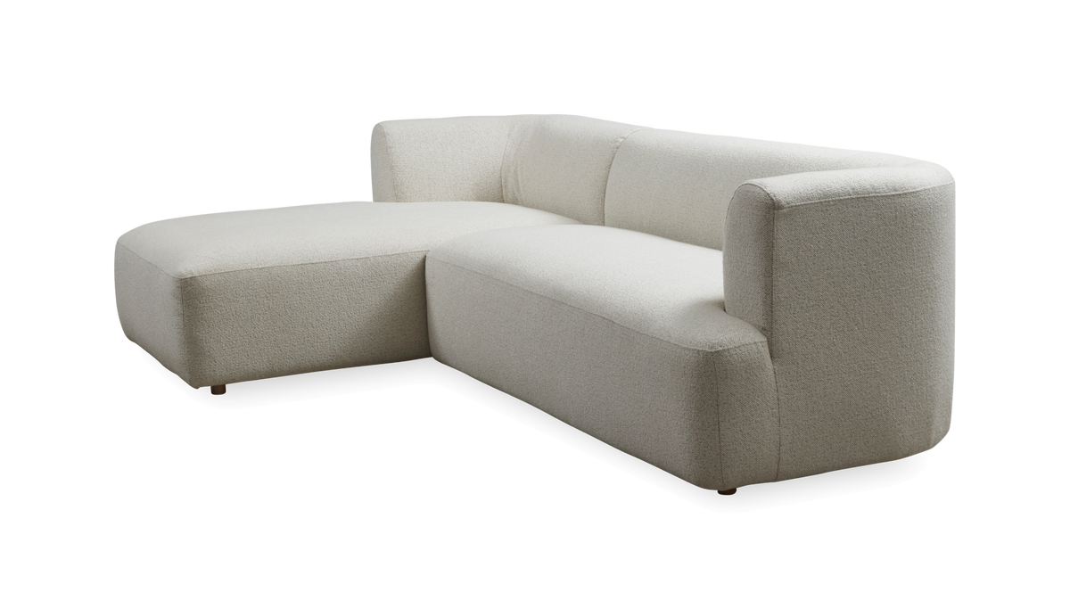L‑sofa med venstrevendt chaiselong i lys beige bouclé, frilagt i studie.