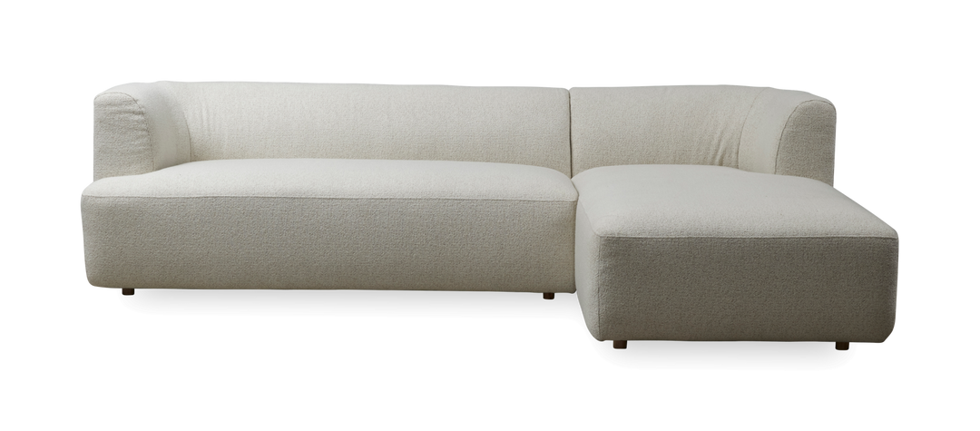 L‑formet sofa i lys beige bouclé med chaiselong til højre.