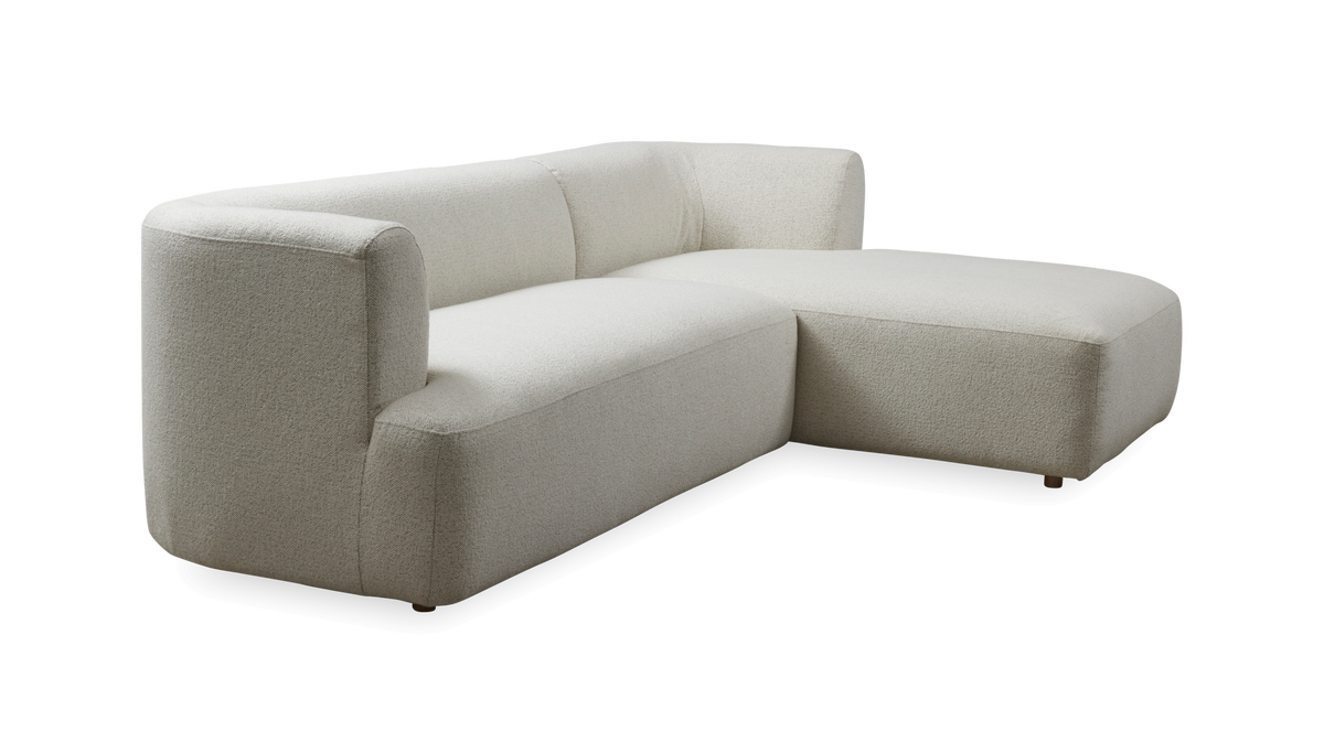 Lys beige hjørnesofa med chaiselong og afrundede former.
