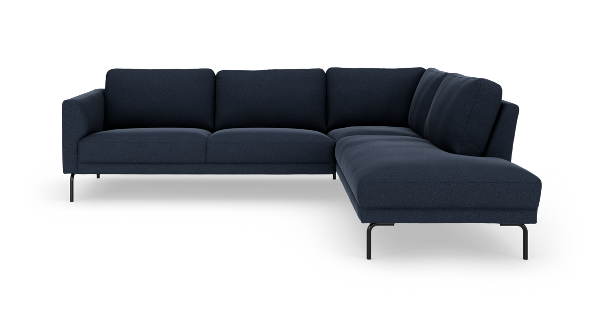 Mørkeblå L‑sofa med chaiselong til højre og slanke sorte ben, frilagt på hvid baggrund.