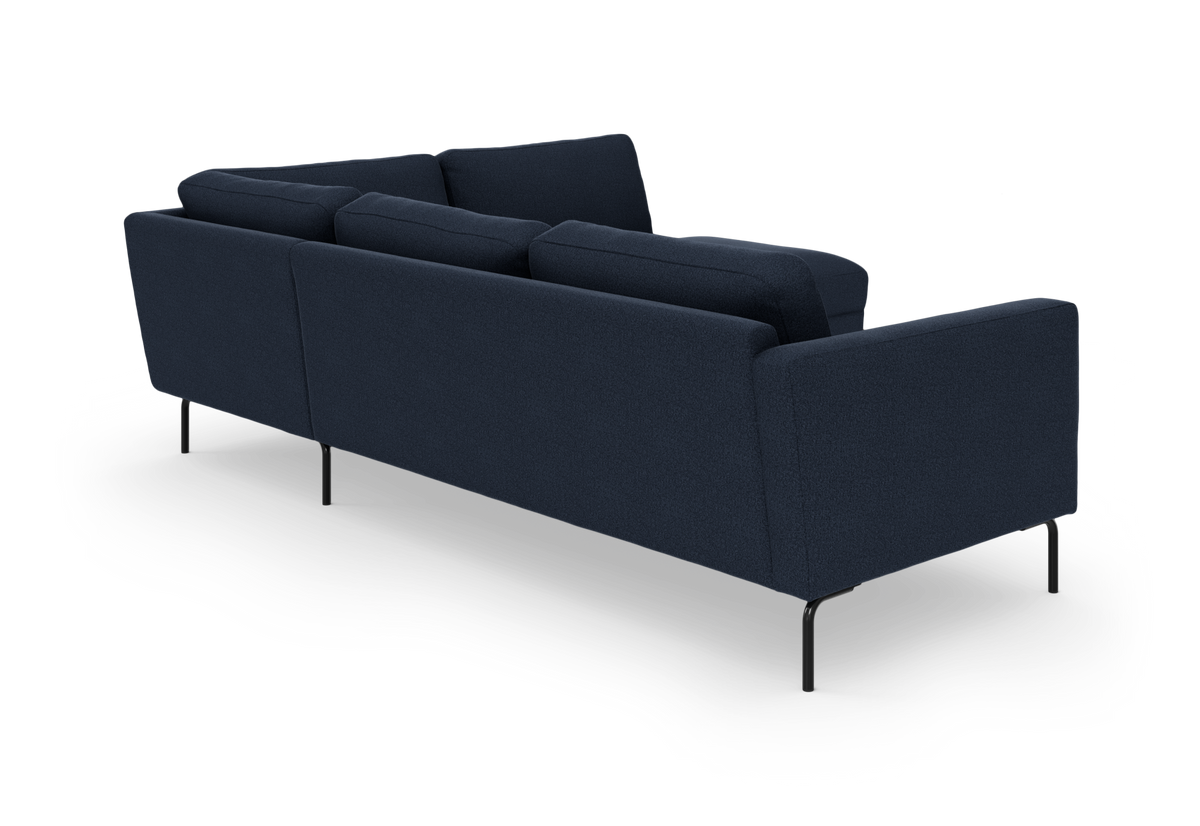 Mørkeblå stofsofa med rene linjer, set bagfra i skrå vinkel; slanke sorte metalben, frilagt på hvid baggrund.