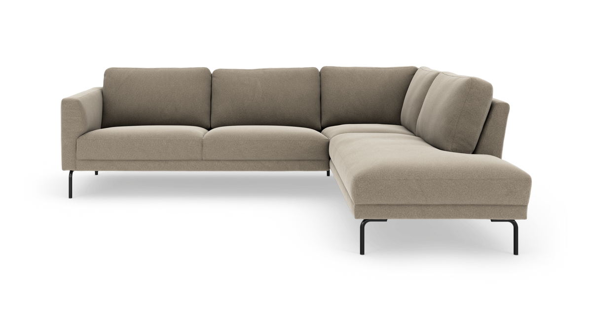 Beige L‑sofa med chaiselong til højre, slanke sorte metalben og bløde hynder.