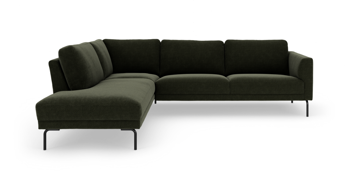 Mørkegrøn L‑sofa med chaiselong til venstre på slanke sorte ben, frilagt på hvid baggrund.