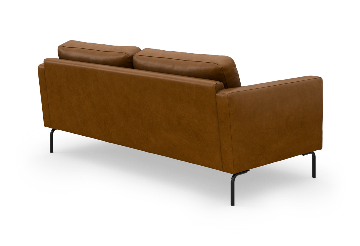 Brun lædersofa med slanke sorte metalben, set skråt bagfra på hvid baggrund.
