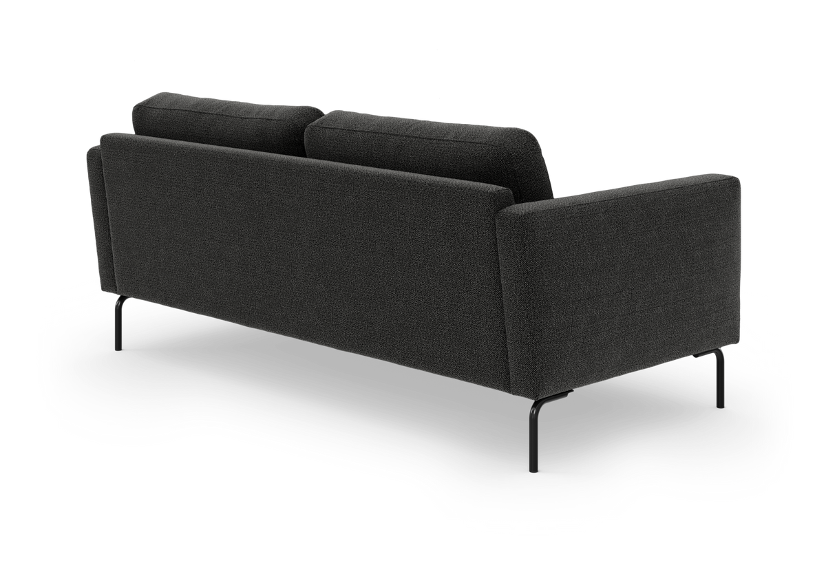 Mørkegrå stofsofa set bagfra med slanke sorte metalben, frilagt på hvid baggrund.