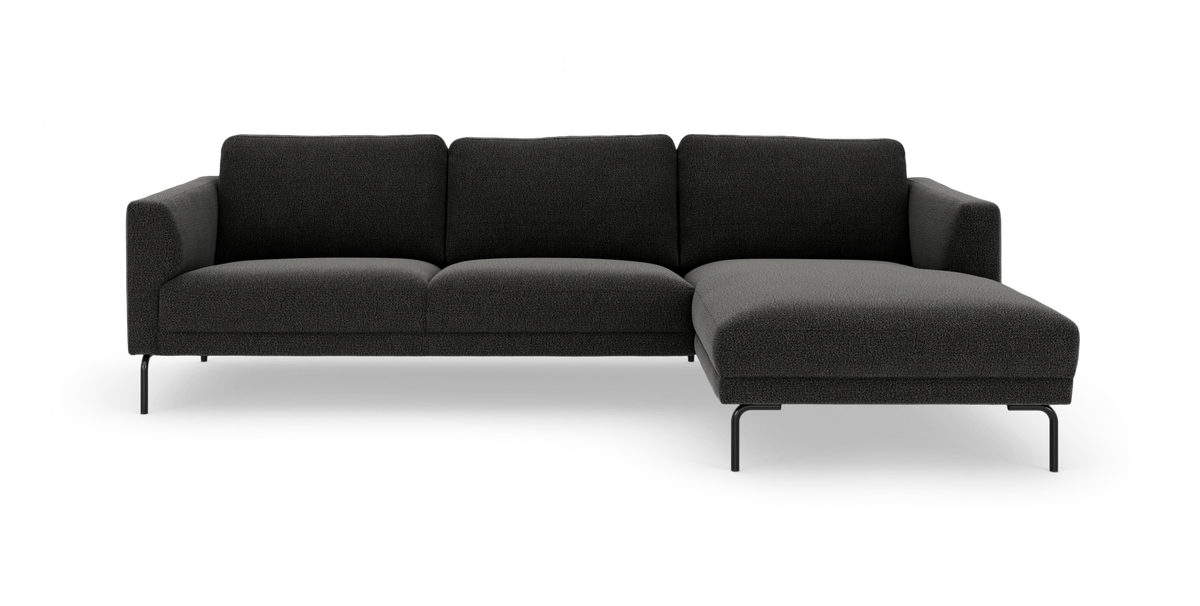 Mørkegrå modulsofa med chaiselong til højre på hvid baggrund.