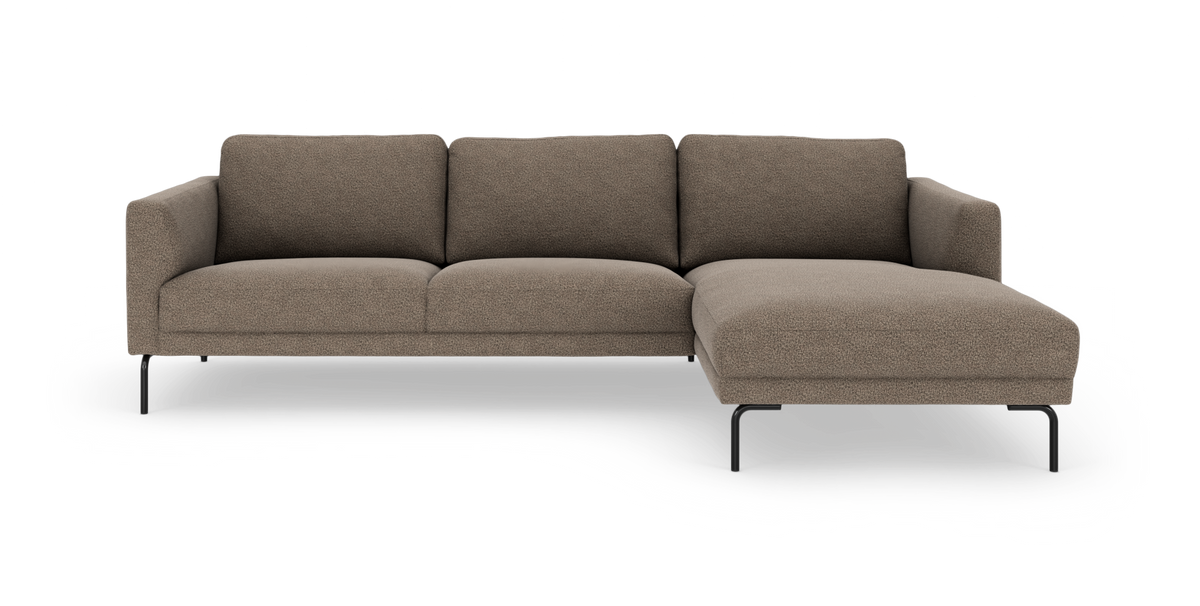 Mørk beige hjørnesofa med chaiselong til højre, slanke sorte metalben og blød bouclébetræk.