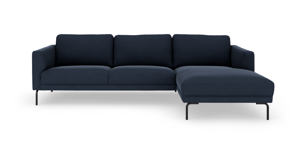 Mørkeblå hjørnesofa med chaiselong til højre, slanke sorte ben.