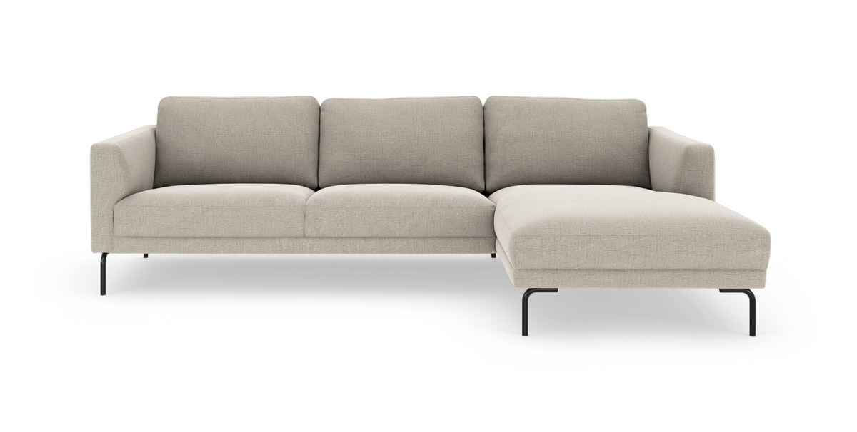Beige L-formet sofa med chaiselong til højre på slanke sorte metalben, set lige forfra.