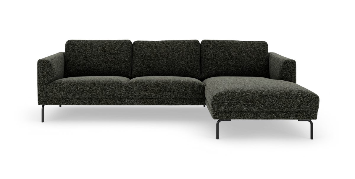 Mørkegrå L‑sofa med chaiselong til højre, slanke sorte ben, frilagt på hvid baggrund.