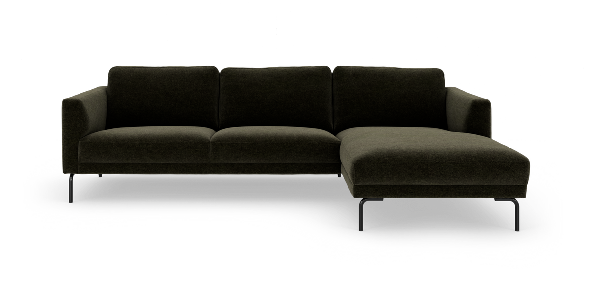 Mørkegrøn hjørnesofa med chaiselong til højre og slanke sorte metalben, frilagt på hvid baggrund.