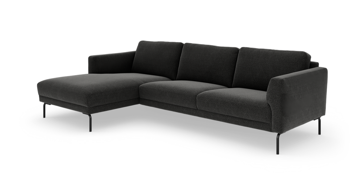 Mørkegrå L‑sofa med venstrevendt chaiselong, slanke sorte metalben og bløde rygpuder, frilagt på hvid baggrund.