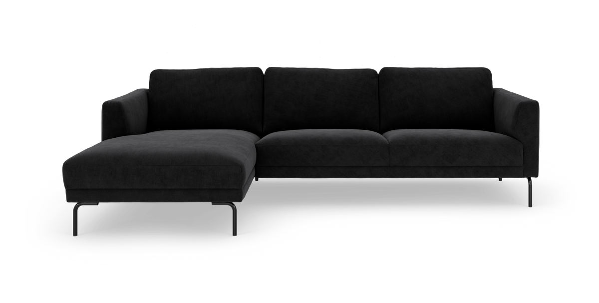 Sort hjørnesofa med chaiselong til venstre på slanke metalben, fritlagt mod hvid baggrund.