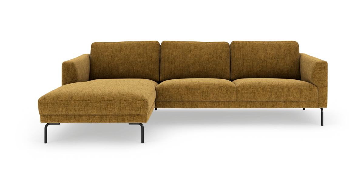 Sennepsgul hjørnesofa med chaiselong til venstre på slanke sorte ben, frilagt på hvid baggrund.
