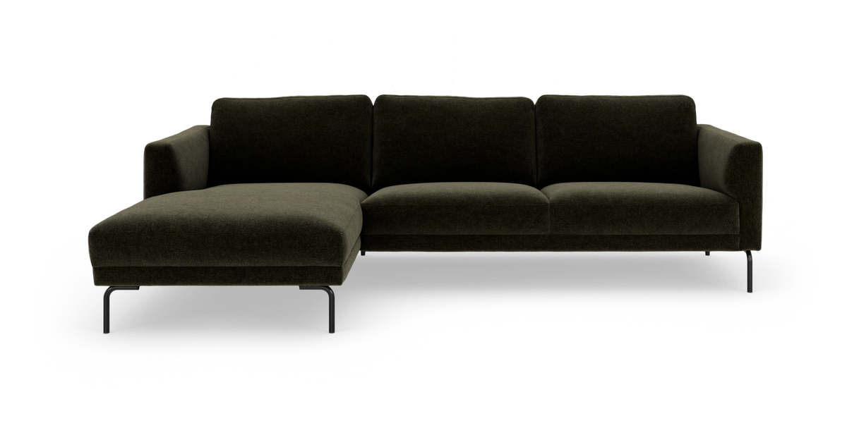 Mørkegrøn hjørnesofa med venstrevendt chaiselong og slanke sorte ben, frilagt på hvid baggrund.