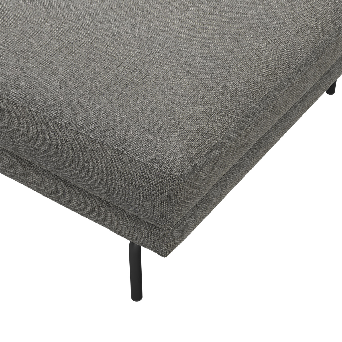 Nærbillede af gråt stofbetrukket sofa- eller ottomanhjørne med slankt sort metalben, frilagt på hvid baggrund.