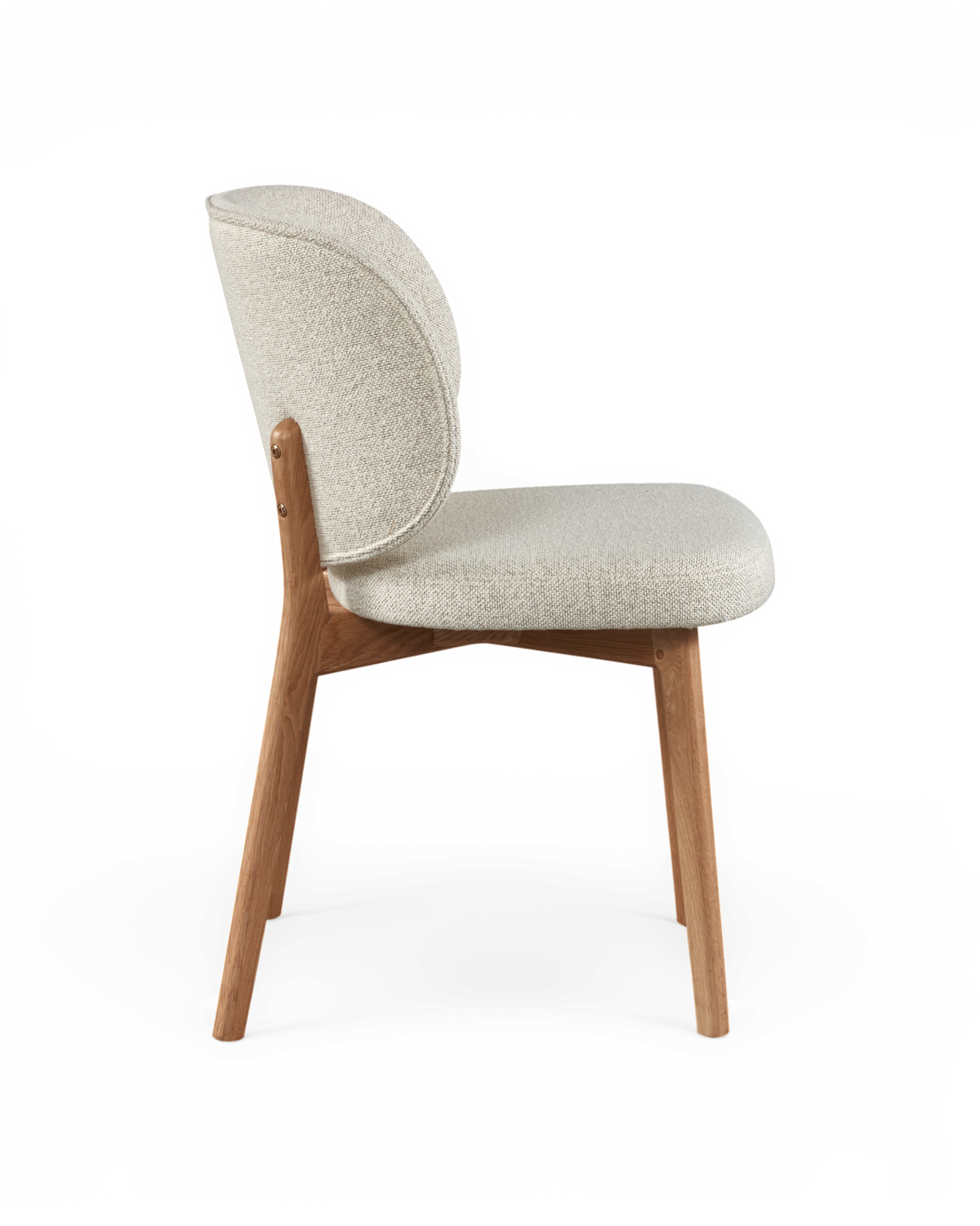 Stol i sideprofil med rund ryg, beige stof og egetræben på frilagt baggrund.