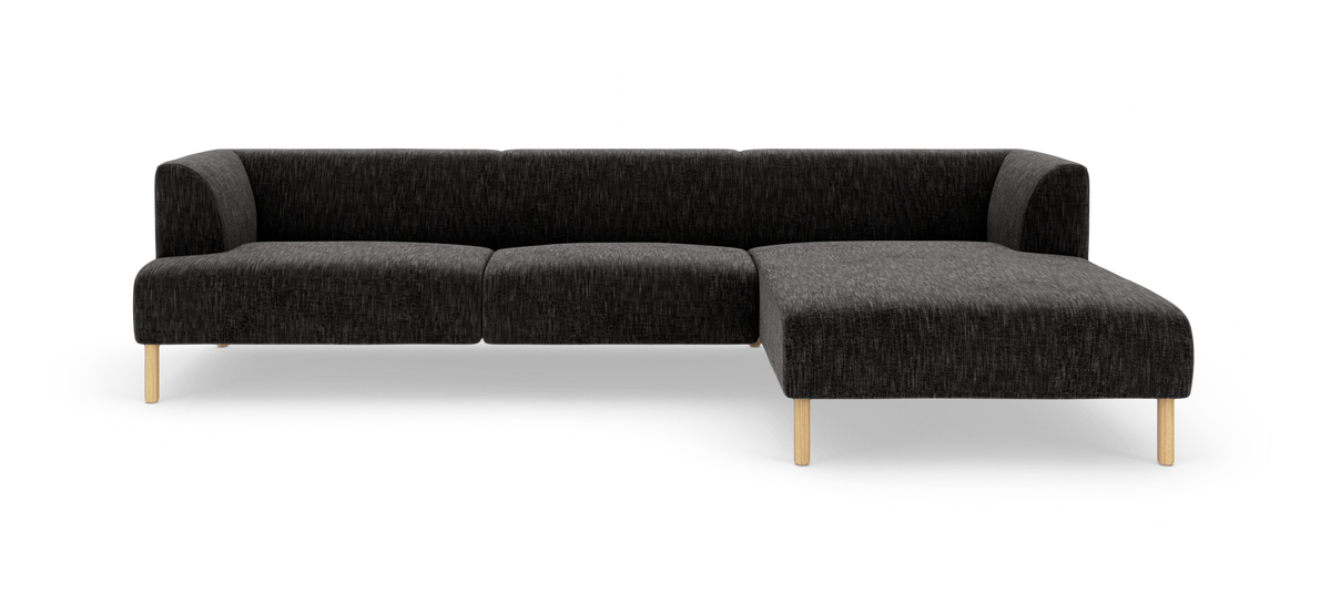 Mørkegrå modulsofa med chaiselong til højre og slanke træben, fotograferet lige for i studiemiljø.