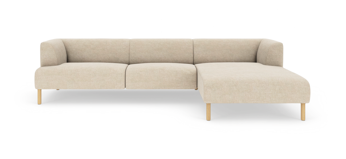 Beige hjørnesofa med chaiselong til højre på lyse træben, frilagt på hvid baggrund.