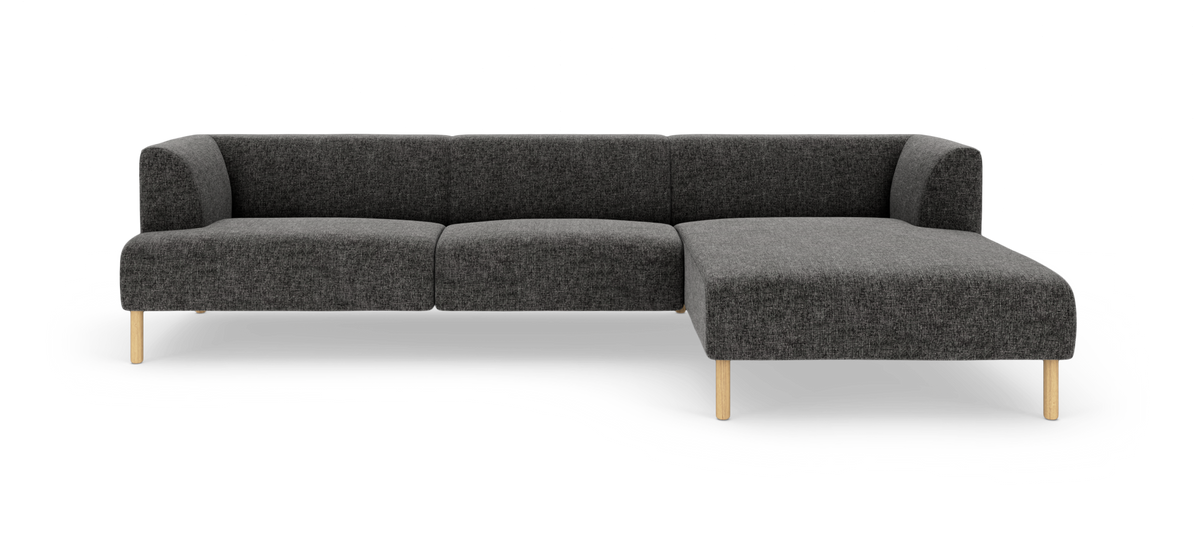 Mørkegrå modulsofa i L‑form med chaiselong til højre og lyse træben.