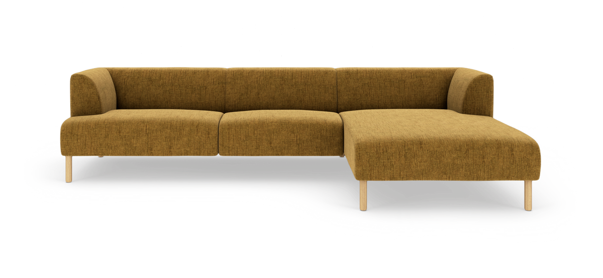 Sennepsgul L‑sofa med højre chaiselong, afrundede armlæn og lyse træben, frilagt på hvid baggrund.
