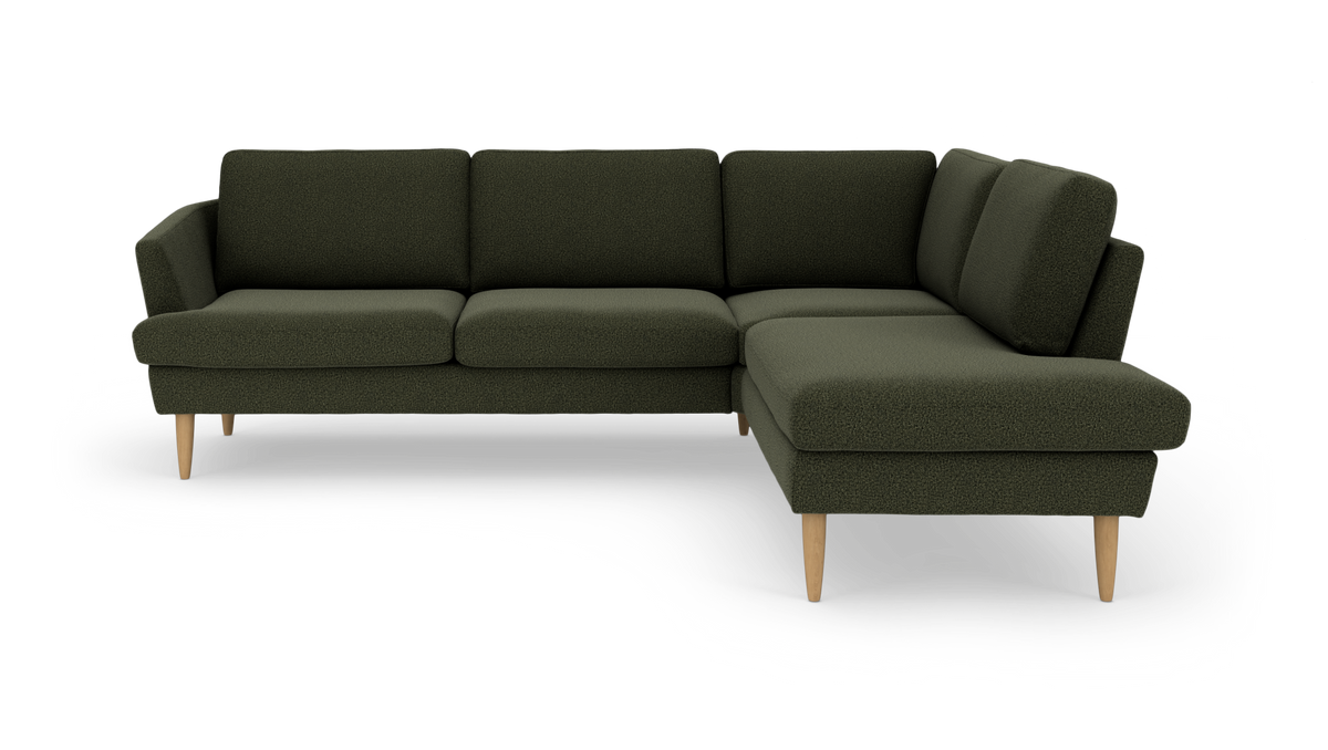 Grøn hjørnesofa med chaiselong til højre og træben, frilagt på hvid baggrund.