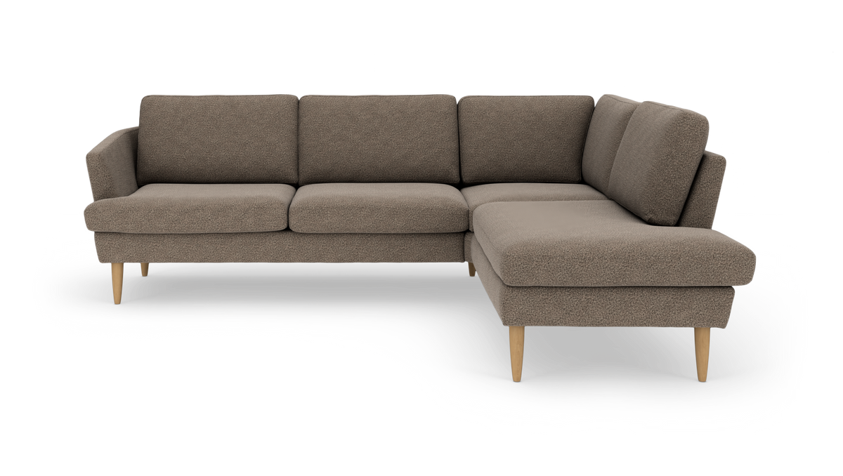 Brun L‑sofa med chaiselong til højre, stofbetræk og koniske ben i lyst træ.