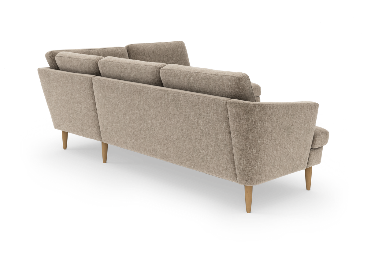 Beige stofsofa med koniske ben i lyst træ, set skråt bagfra på hvid baggrund.