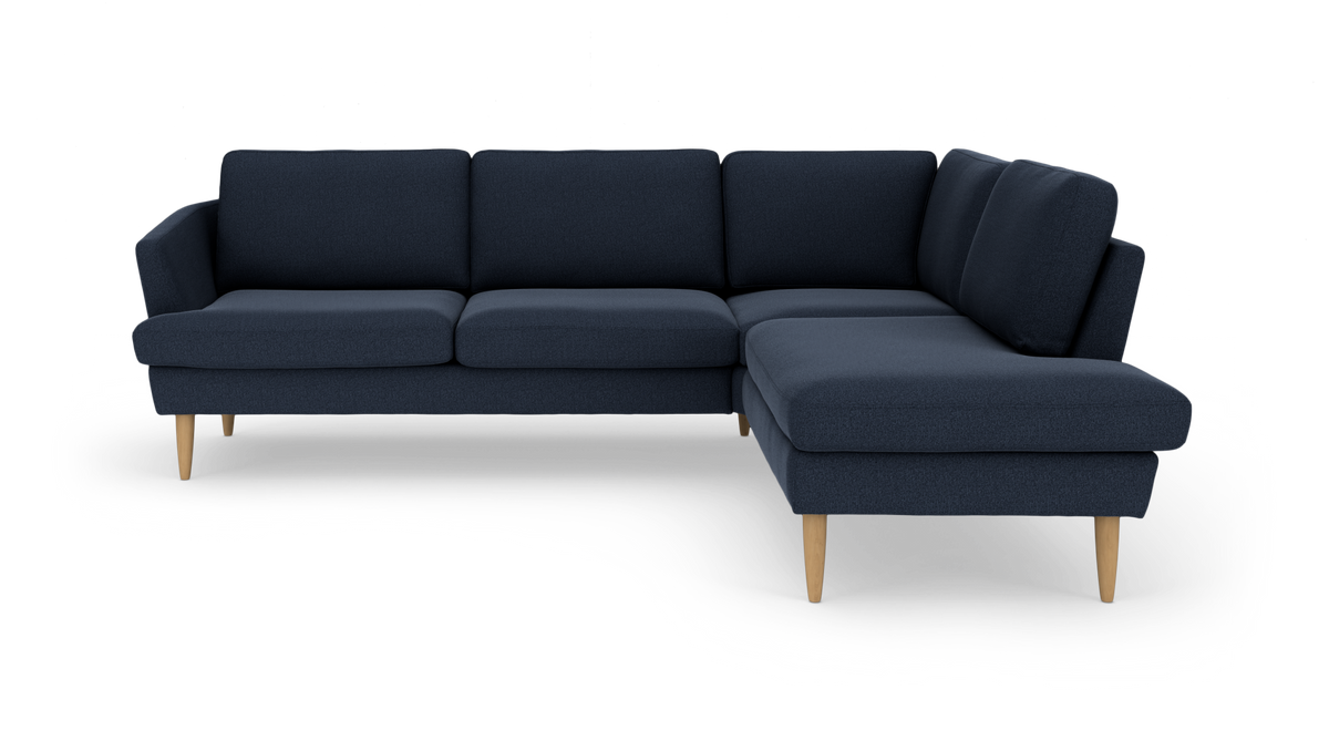 Mørkeblå hjørnesofa med chaiselong til højre og lyse træben.