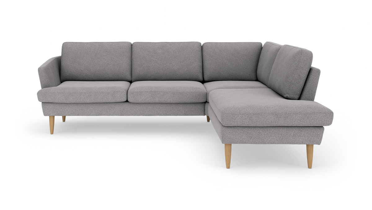 Grå L-formet hjørnesofa med chaiselong til højre, træben, på hvid baggrund.