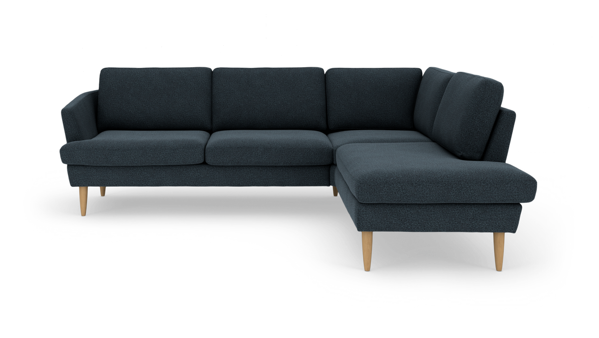 Mørkeblå hjørnesofa med chaiselong til højre og lyse træben.