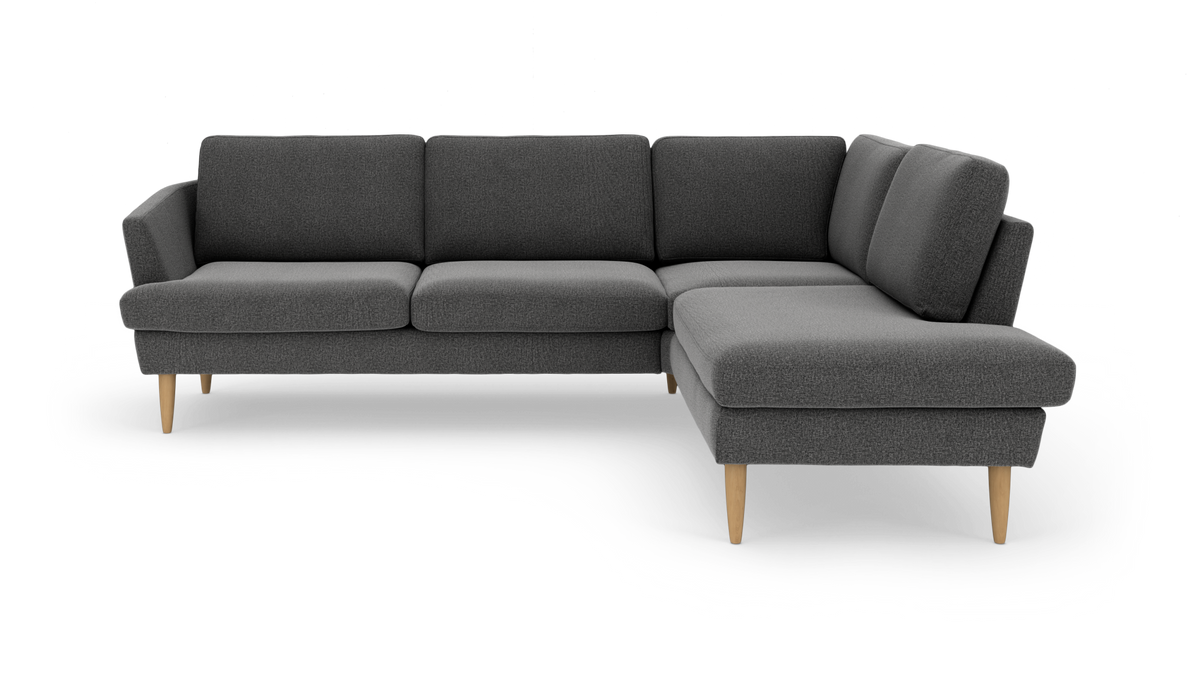 Mørkegrå hjørnesofa med chaiselong til højre og lyse træben, frilagt på hvid baggrund.