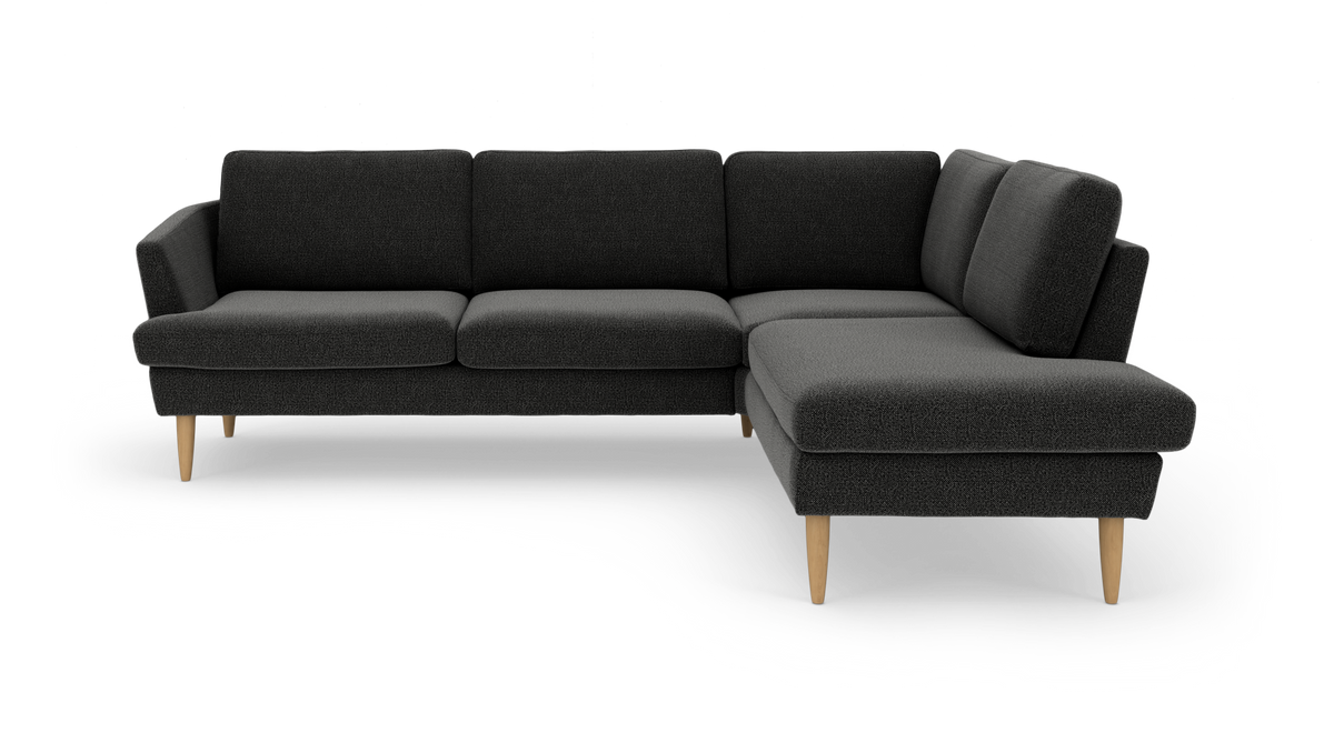 Mørkegrå hjørnesofa med chaiselong til højre og lyse træben.