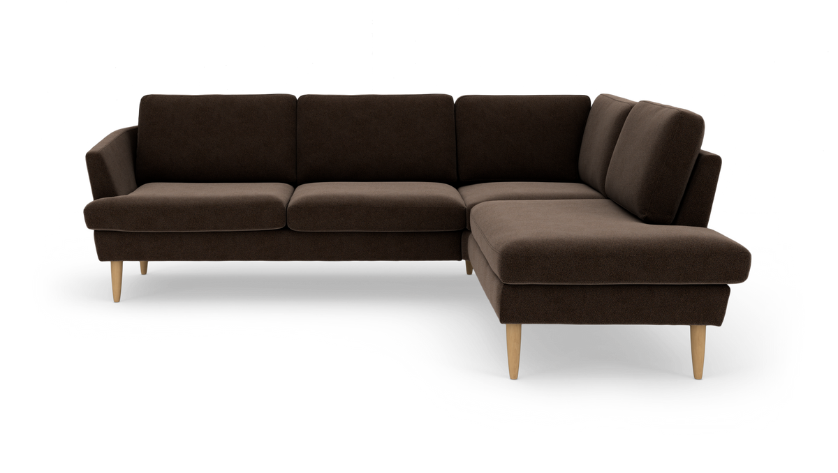 Hjørnesofa i mørkebrunt stof med chaiselong til højre og lyse træben, frilagt på hvid baggrund.